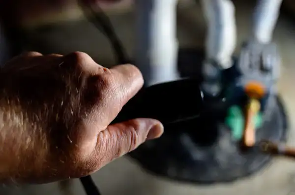 A hand with a remote control, pointed towards a partially blurred figurine in the background, subtly echoes the precision needed for a sump pump install.