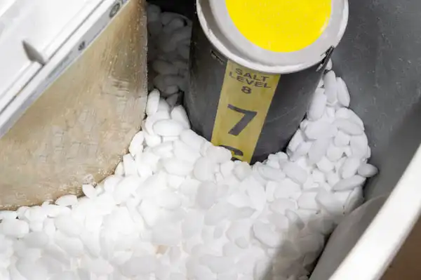 Salt pellets fill a water softener container, surrounding a yellow and black indicator tube that shows the salt level at 7, ensuring smooth operation without needing immediate water softener repair.